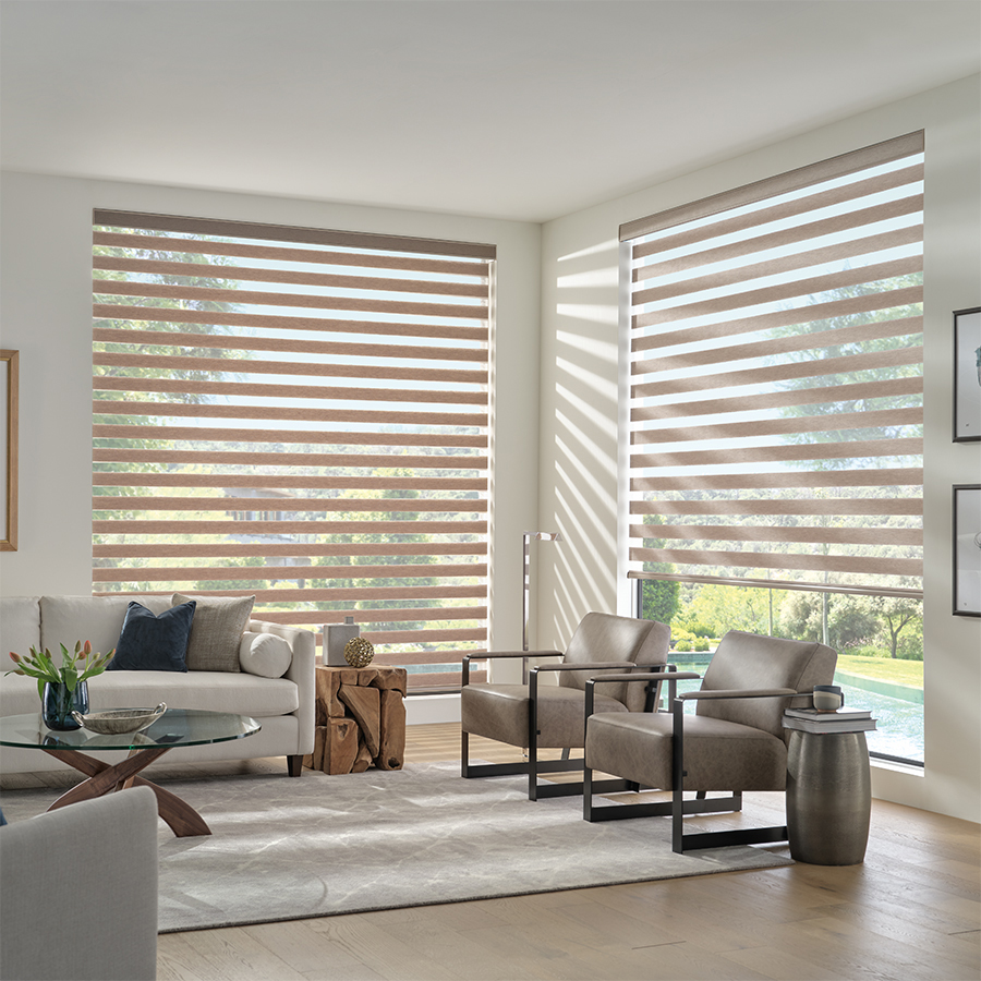 Modern living room with dual-layered designer banded shades filtering sunlight through tall windows, showcasing custom shades in Bozeman.