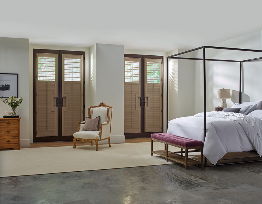 Classic Heritance hardwood Bozeman shutters in rich wood tones bring warmth and timeless design to a sophisticated bedroom suite.