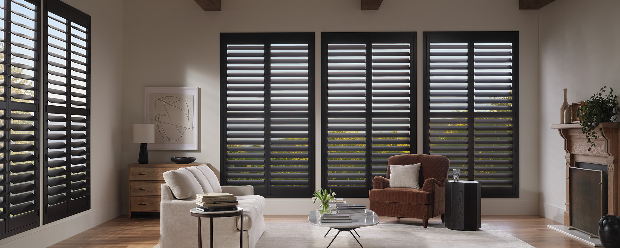 Dark-toned Bozeman shutters frame large living room windows with elegance, offering versatile light control in a contemporary open-concept space.