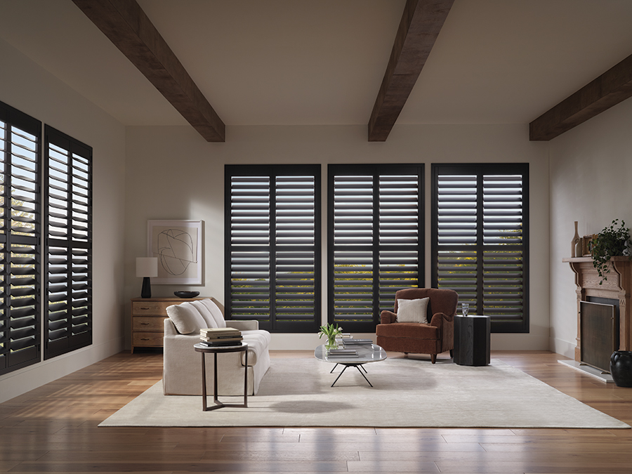 Dark-toned Bozeman shutters frame large living room windows with elegance, offering versatile light control in a contemporary open-concept space.