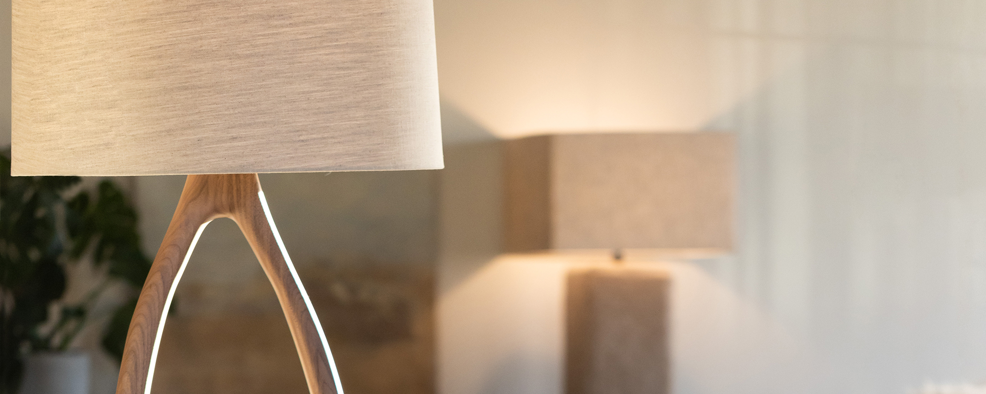 A Verellen “Urbino” floor lamp. This Sculptural floor lamp with an open oval frame and white drum shade stands beside a neutral upholstered chair.